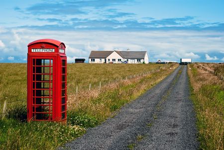 red phone booth standing alone in landscapeの写真素材