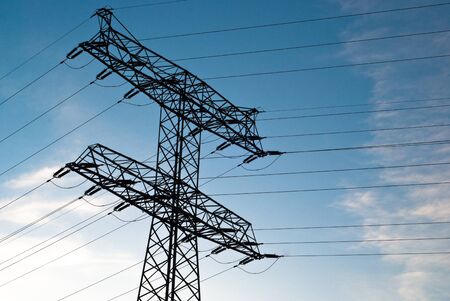 large electricity pylon against blue sky with clouds