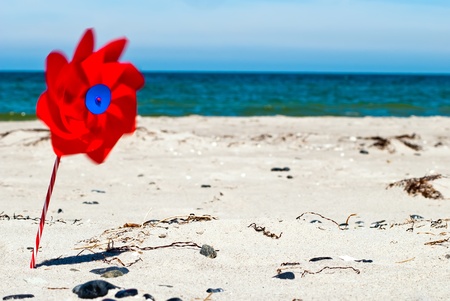 a red wind turbine on the sandy beach with sea in the backgroundの写真素材