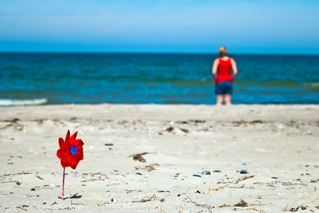 a red wind turbine on the sandy beach with sea in the backgroundの写真素材