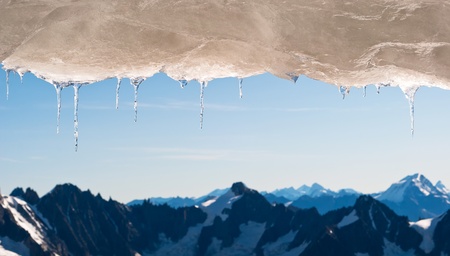 many icicles hang before snow covered mountain landscapeの写真素材