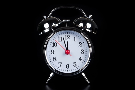 an oldfashioned alarm clock isolates before black backgroundの写真素材