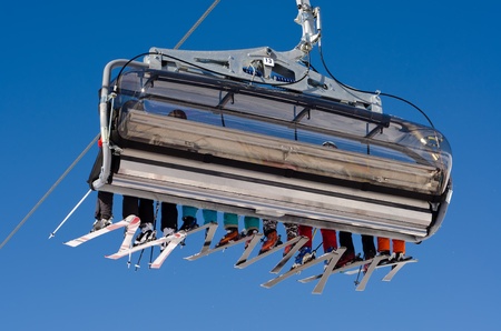 a ski lift with eight skiers before blue skyのeditorial素材