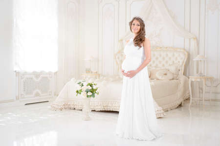 happy pregnant woman in a light interiorの写真素材