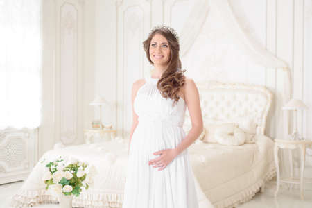 happy pregnant woman in a light interiorの写真素材
