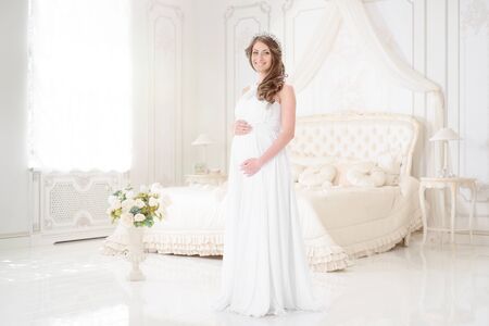 happy pregnant woman in a light interiorの写真素材