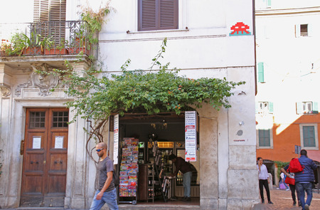 Invader art or space invader art street mosaic on a wall above a shop in a square in Rome, Italy by the French urban or street artist known as Invaderのeditorial素材