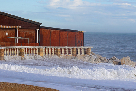 Rough sea in winter in Porto Recanati in the province of Ancona Italy near Monte Conero with the sea crashing against rocks and a boarded up restaurantの写真素材