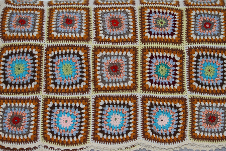 brightly coloured crocheted panels in a homemade woollen blanket with a mosaic designの写真素材