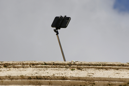 A selfie stick appearing from above a wall on the Spanish Steps in Rome, Italyの写真素材