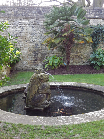 goldfish pond with 17th century statues of 2 heraldic beasts made from limestone in the Fellowsâ Garden in Trinity college Oxford a walled garden with palms and other exotic plantsのeditorial素材