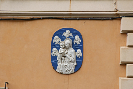 detail of an ancient plaque on a wall in the streets of Rome, Italy showing the Virgin Mary or Madonna and child with angels surrounding themの写真素材