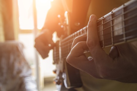 The man is playing the guitar in his house