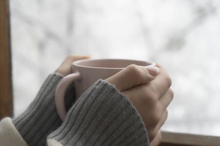 A cup of aromatic coffee in the hands of a girl, winter day, beautiful snowfall