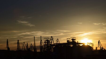 View of the industrial area with many cranes, silhouettes, sunsetの写真素材