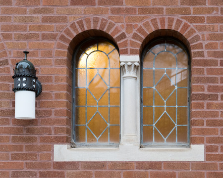 A pair of windows and a lamp on a brick church wall.の写真素材