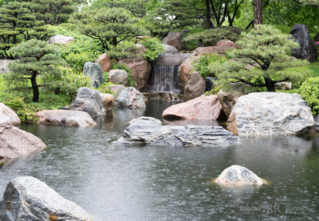 A waterfall drops into a pond in a Japanese gardenの写真素材