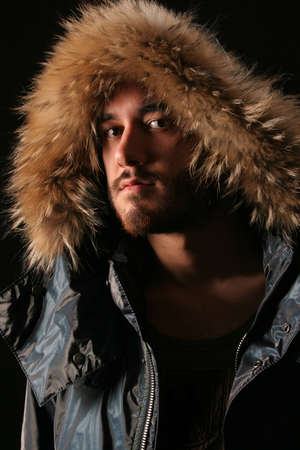 Portrait of a young black background, green shirt and winter jacketの写真素材