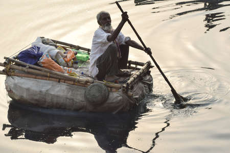 New Delhi, India - March 04, 2020: A man paddling a boat during morning time at Yamuna river ghat in New Deli, Indiaのeditorial素材