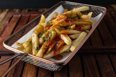 Sticky honey Chilli potatoes in a spicy sauce, sesame seeds and green onions close-up on a plate on the table. horizontal top view from top side, Chilli Potatoの写真素材