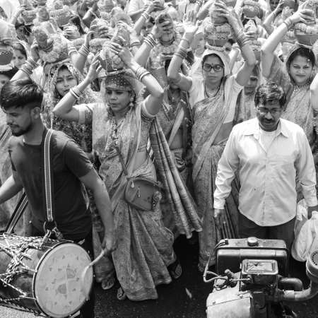 Delhi, India April 03 2022 - Women with Kalash on head during Jagannath Temple Mangal Kalash Yatra, Indian Hindu devotees carry earthen pots containing sacred water with coconut on top-Black and Whiteのeditorial素材
