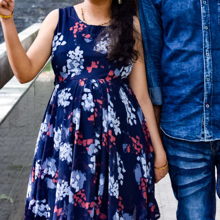 Indian couple posing for maternity baby shoot. The couple is posing in a lawn with green grass and...