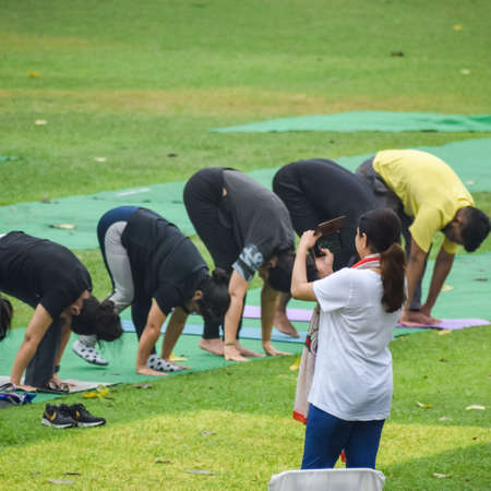 New Delhi, India, June 18 2022 - Group Yoga exercise class Surya Namashkar for people of different age in Lodhi Garden, International Yoga Day, Big group of adults attending a yoga class in parkのeditorial素材