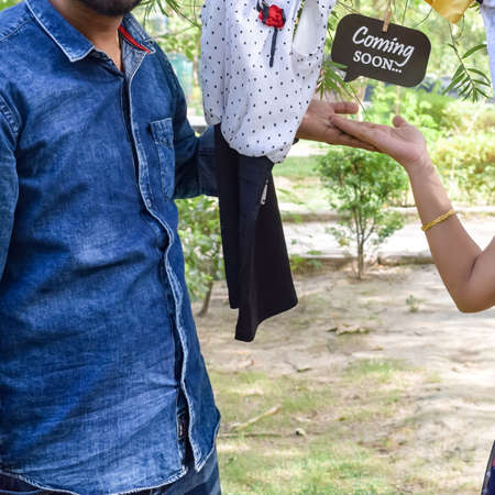 Indian couple posing for maternity baby shoot. The couple is posing in a lawn with green grass and the woman is falunting her baby bump in Lodhi Garden in New Delhi, Indiaの写真素材