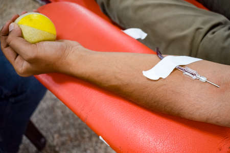 Blood donor at Blood donation camp held with a bouncy ball holding in hand at Balaji Temple, Vivek Vihar, Delhi, India, Image for World blood donor day on June 14 every year, Blood Donation Campの写真素材