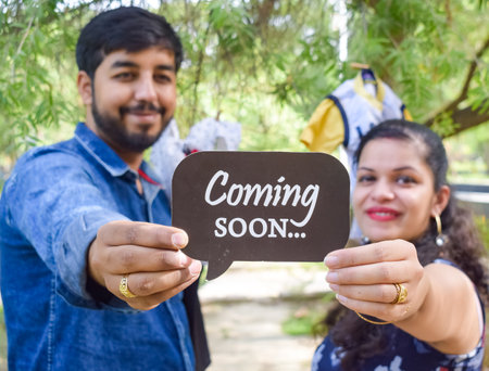 Indian couple posing for maternity baby shoot. The couple is posing in a lawn with green grass and the woman is falunting her baby bump in Lodhi Garden in New Delhi, Indiaの写真素材