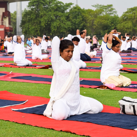 New Delhi, India, June 21 2022 - Group Yoga exercise session for people at Yamuna Sports Complex in Delhi on International Yoga Day, Big group of adults attending yoga class in cricket stadiumのeditorial素材