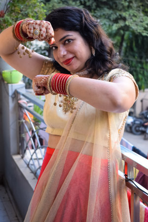 Beautiful woman dressed up as Indian tradition with henna mehndi design on her both hands to...