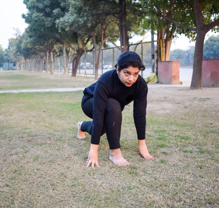 Young Indian woman practicing yoga outdoor in a park. Beautiful girl practice basic yoga pose. Calmness and relax, female happiness. Basic Yoga poses outdoorの写真素材