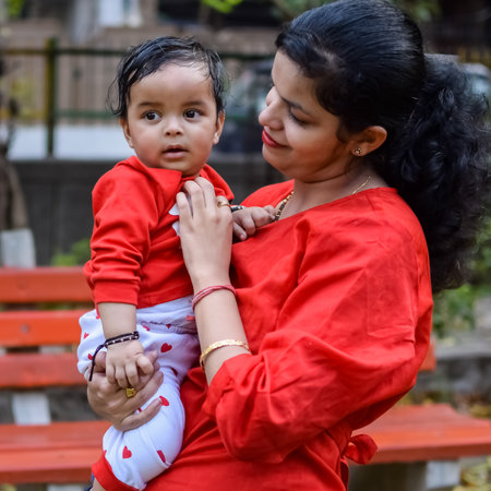 Loving mom carrying of her baby at society park. Bright portrait of happy mum holding child in her hands. Mother hugging her little 9 months old son.の写真素材