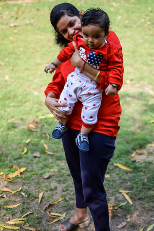 Loving mom carrying of her baby at society park. Bright portrait of happy mum holding child in her...