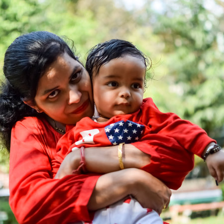 Loving mom carrying of her baby at society park. Bright portrait of happy mum holding child in her hands. Mother hugging her little 9 months old son.の写真素材