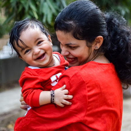 Loving mom carrying of her baby at society park. Bright portrait of happy mum holding child in her hands. Mother hugging her little 9 months old son.の写真素材