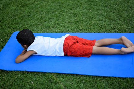 Asian smart kid doing yoga pose in the society park outdoor, Children's yoga pose. The little boy doing Yoga and meditation exercise.の写真素材