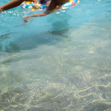 Happy Indian boy swimming in a pool, Kid wearing swimming costume along with air tube during hot summer vacations, Children boy in big swimming pool.の写真素材