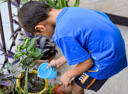 Cute 5 yearâs old Asian little boy is watering the plant in the pots located at house balcony. Love of sweet little boy for the mother nature during watering into plants. Kid Plantingの写真素材