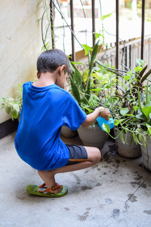 Cute 5 yearâs old Asian little boy is watering the plant in the pots located at house balcony. Love of sweet little boy for the mother nature during watering into plants. Kid Plantingの写真素材