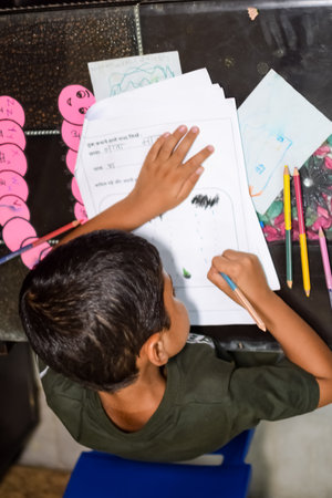 Smart Indian little boy drawing with colourful pencils kit of various colours during the summer...
