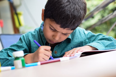 Smart Indian little boy perform thumb painting with different colourful water colour kit during the...