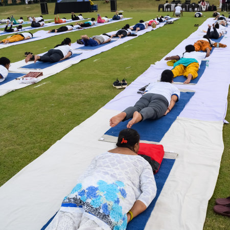 New Delhi, India, June 21, 2023 - Group Yoga exercise session for people at Yamuna Sports Complex in Delhi on International Yoga Day, Big group of adults attending yoga class in cricket stadiumのeditorial素材