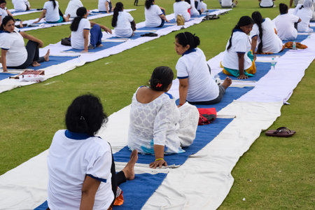 New Delhi, India, June 21, 2023 - Group Yoga exercise session for people at Yamuna Sports Complex in Delhi on International Yoga Day, Big group of adults attending yoga class in cricket stadiumのeditorial素材
