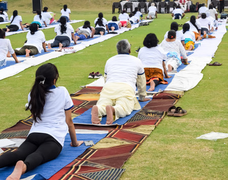 New Delhi, India, June 21, 2023 - Group Yoga exercise session for people at Yamuna Sports Complex in Delhi on International Yoga Day, Big group of adults attending yoga class in cricket stadiumのeditorial素材