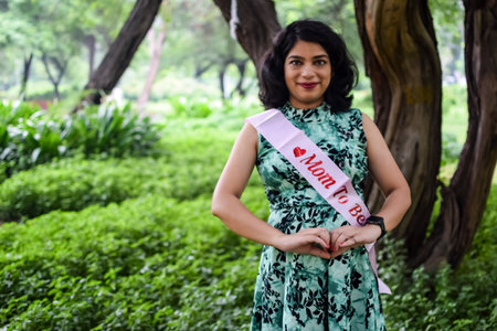 A pregnant Indian lady poses for outdoor pregnancy shoot and hands on belly, Indian pregnant woman...