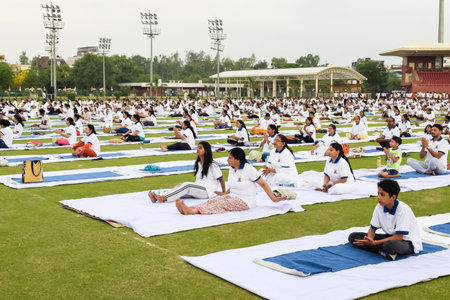New Delhi, India, June 21, 2023 - Group Yoga exercise session for people at Yamuna Sports Complex in Delhi on International Yoga Day, Big group of adults attending yoga class in cricket stadiumのeditorial素材