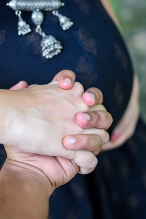 A pregnant Indian lady poses for outdoor pregnancy shoot and hands on belly, Indian pregnant woman puts her hand on her stomach with a maternity dress at society park, Pregnant outside maternity shootの写真素材