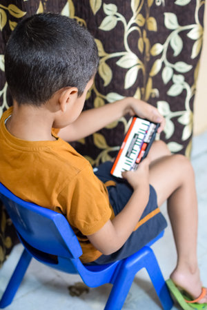 Portrait of Asian smart happy little boy using Mobile phone at home. Little boy holding mobile smart phone, online back to school concept. Online Class conceptの写真素材